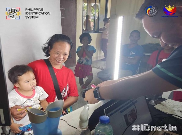 A registration officer takes photo of a child during PhilSys enrolment.