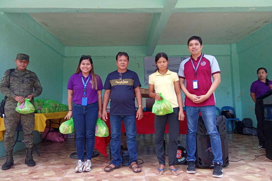 A beneficiary (in yellow blouse) receives a grocery pack from PhilSys personnel during the gift-giving activity in Brgy. Loctuga, Libacao